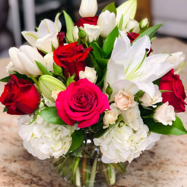 Bouquet of red and white roses with white lilies in a glass vase