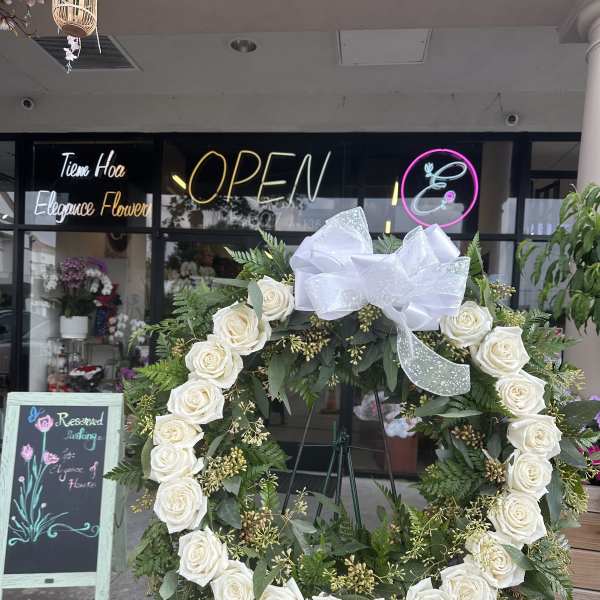 White rose wreath with a large white bow on an easel