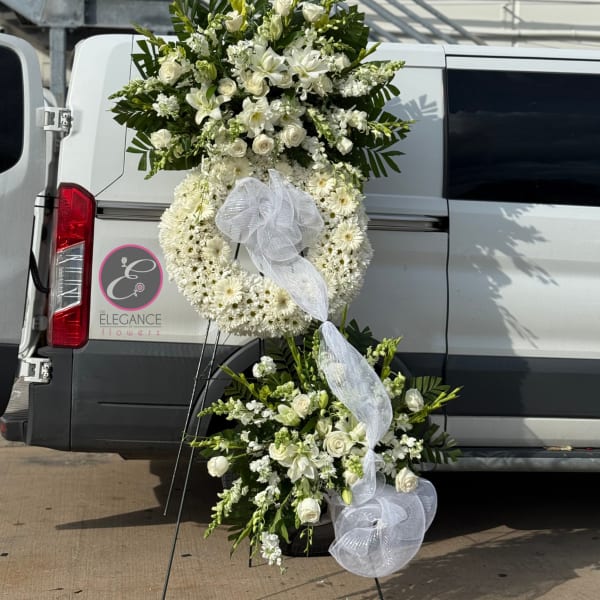 White floral funeral wreath and spray with ribbon on a stand