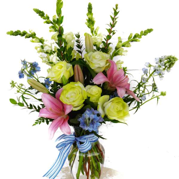 Bouquet of pink lilies and pale yellow roses in a glass vase with a blue ribbon