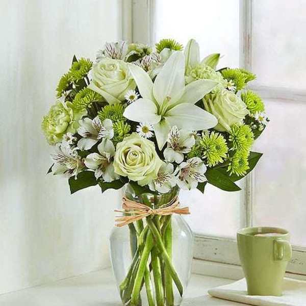 White lilies and pale roses in a clear glass vase