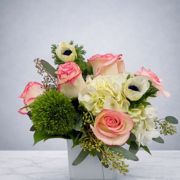 Pink-edged roses and white blooms in a square glass vase