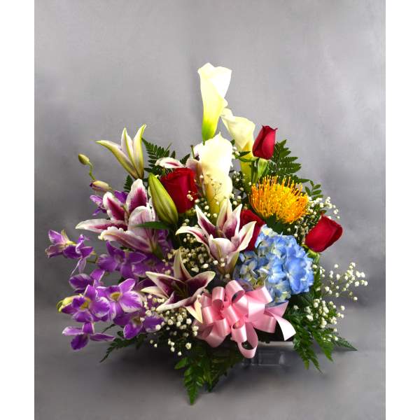 Mixed bouquet with lilies, roses, hydrangea, and a pink ribbon