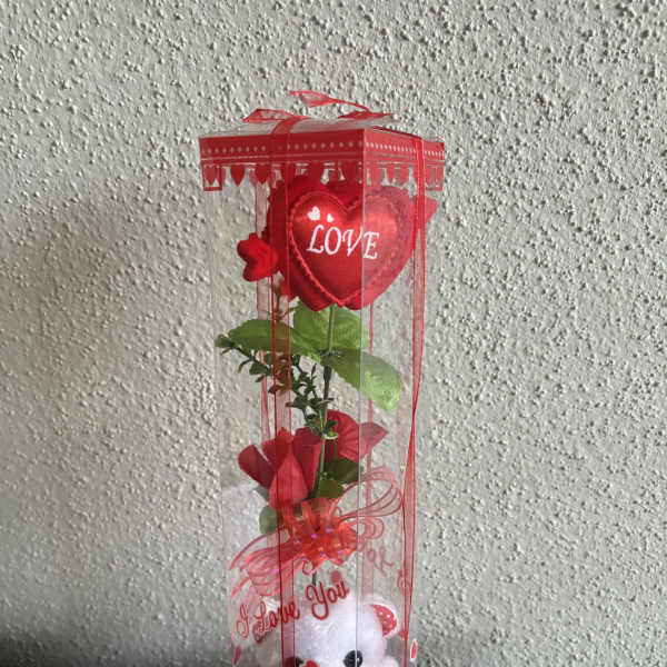 Red heart-themed gift box with a teddy bear and artificial rose stem
