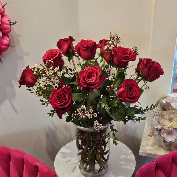 Red roses arranged in a clear glass vase on a small round table