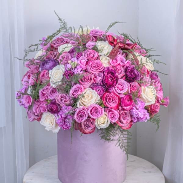 Large bouquet of pink, purple, and white roses in a lavender box