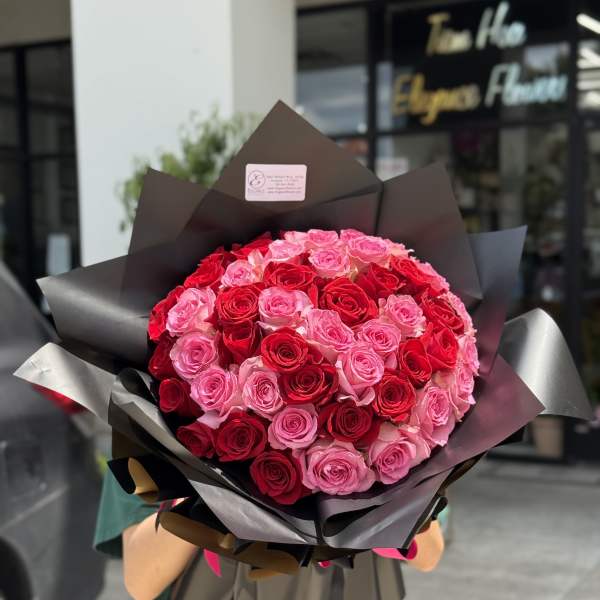 Large bouquet of red and pink roses wrapped in dark paper