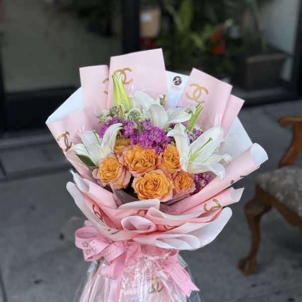Bouquet of orange roses and white lilies wrapped in pink paper