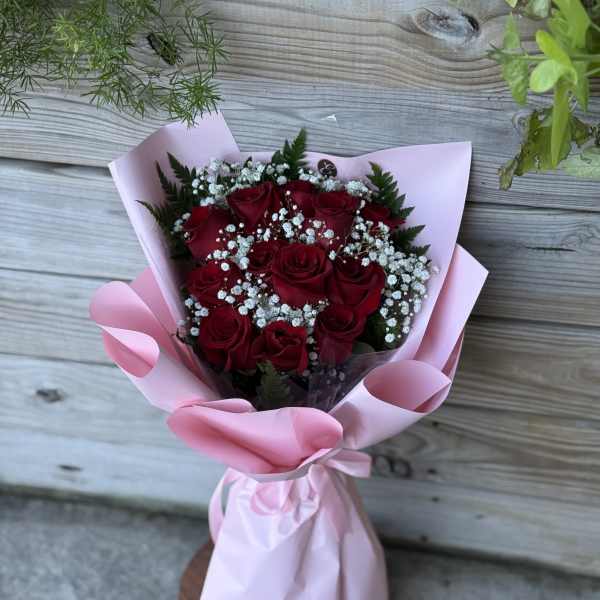 Bouquet of red roses with baby's breath wrapped in pink paper