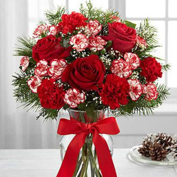 Red roses and carnations in a glass vase with a red ribbon