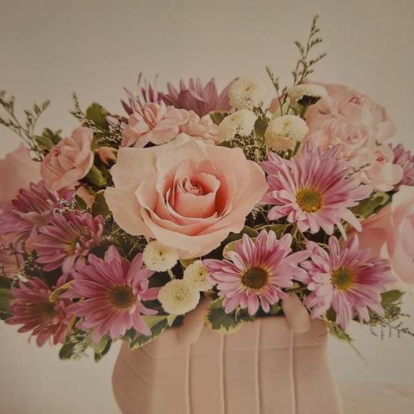 Pink roses and daisies arranged in a blush vase