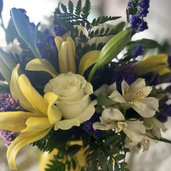Bouquet of yellow lilies, white roses, and white alstroemeria with purple accents