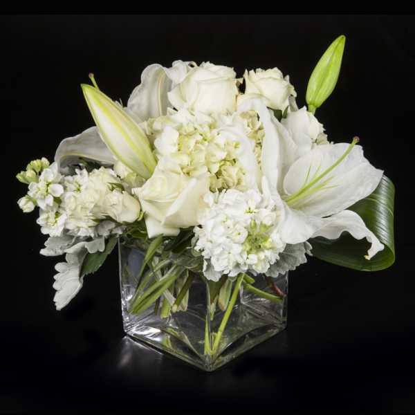 White floral arrangement in a clear square glass vase