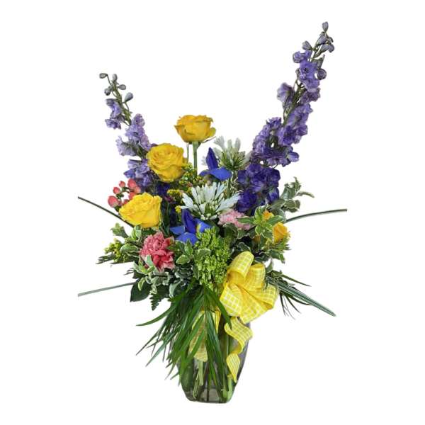 Tall mixed bouquet with yellow roses, purple flowers, and a yellow ribbon in a glass vase