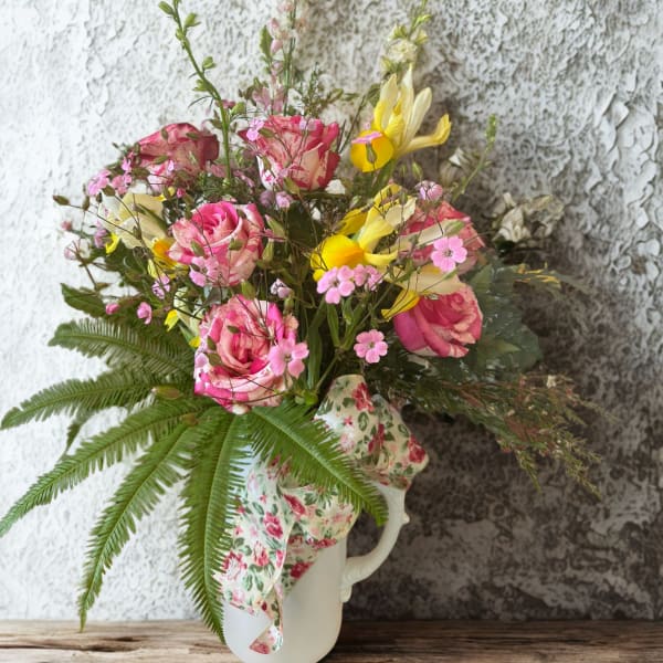 Pink and yellow mixed bouquet in a white pitcher vase