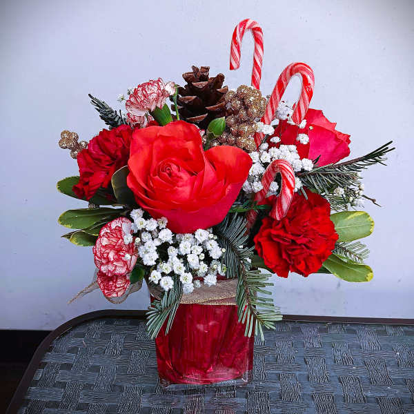 Red roses and carnations in a red vase with candy canes and pinecones