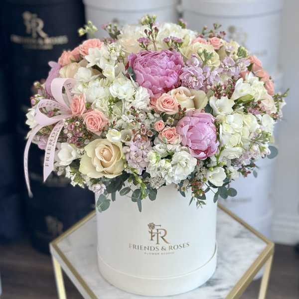 Pink and white roses arranged in a white hat box