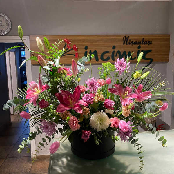 Large pink and white floral arrangement in a black container