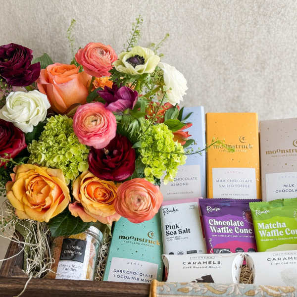 Mixed bouquet beside assorted chocolates and caramels in a wooden gift box