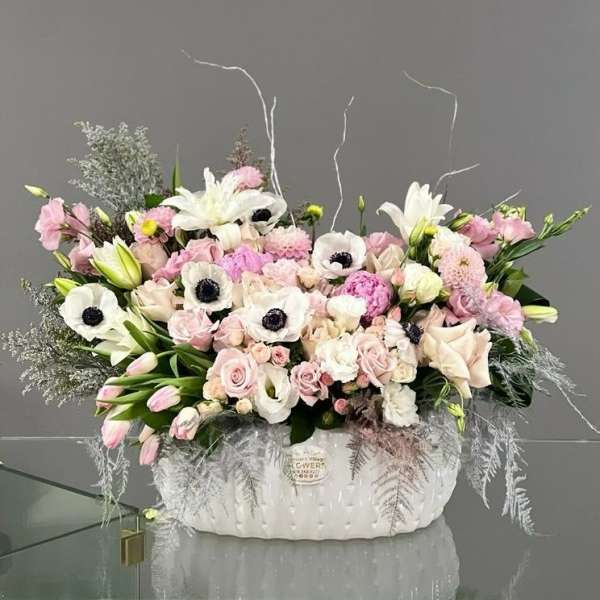 Large pastel flower arrangement in a white ceramic container