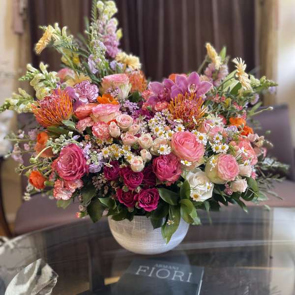 Large mixed bouquet in a white vase with pink, orange, and white blooms
