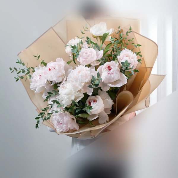 Bouquet of pale pink peonies wrapped in tan paper