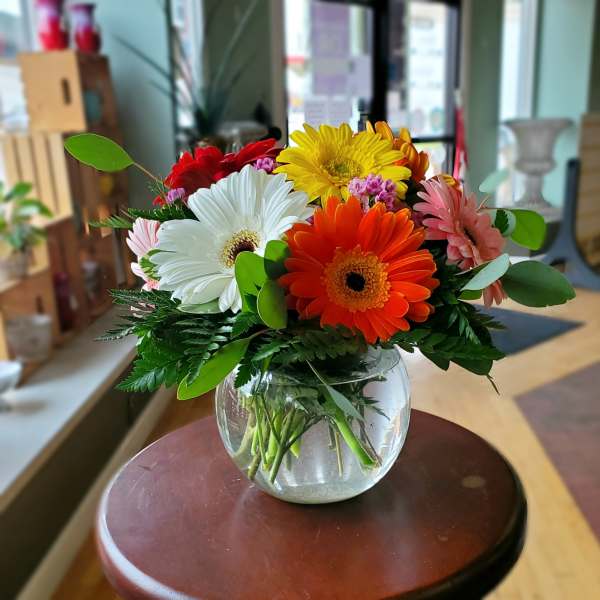 Colorful gerbera daisy bouquet in a round glass vase