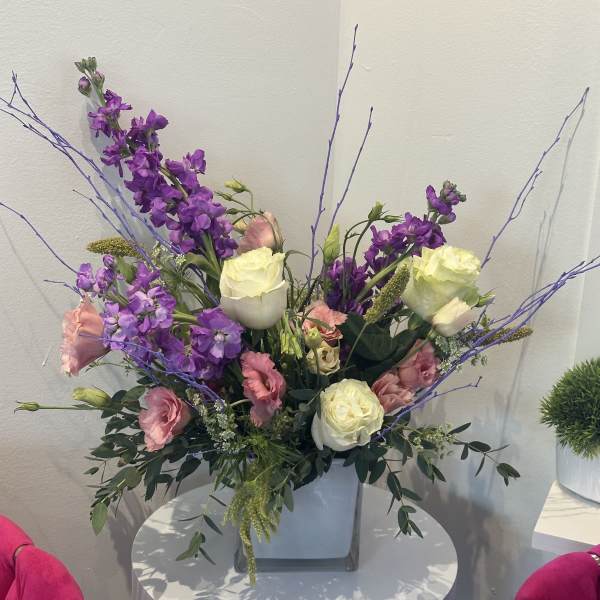 Purple and pink floral arrangement in a square vase with long branches