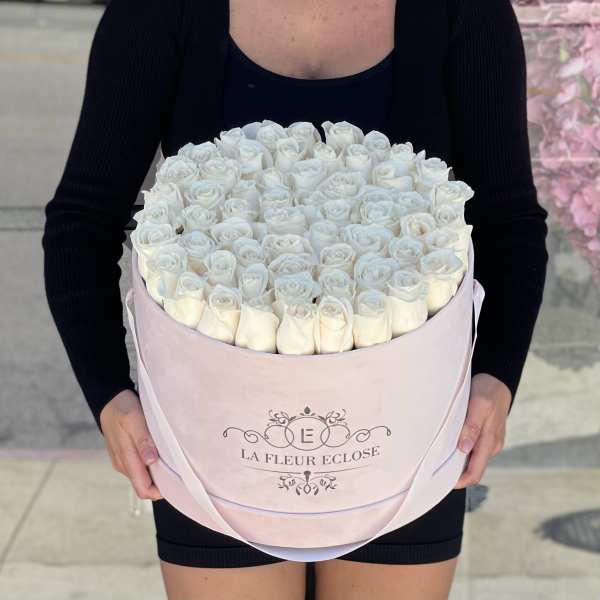 Round box of white roses held by a person in black clothing