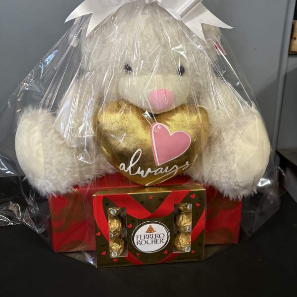 Plush teddy bear holding a gold heart and Ferrero Rocher chocolates in gift wrap