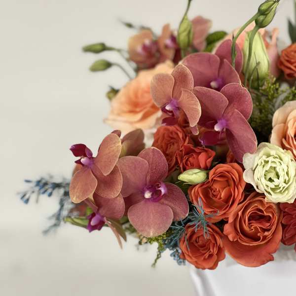 Bouquet of pink orchids and orange roses in a white wrap
