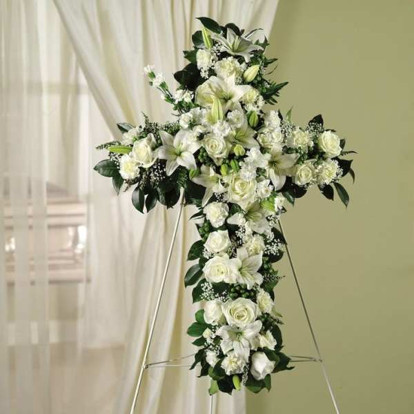 White floral cross arrangement on a stand