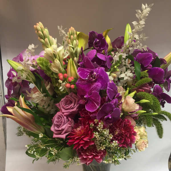 Purple orchid and rose bouquet in a clear glass vase