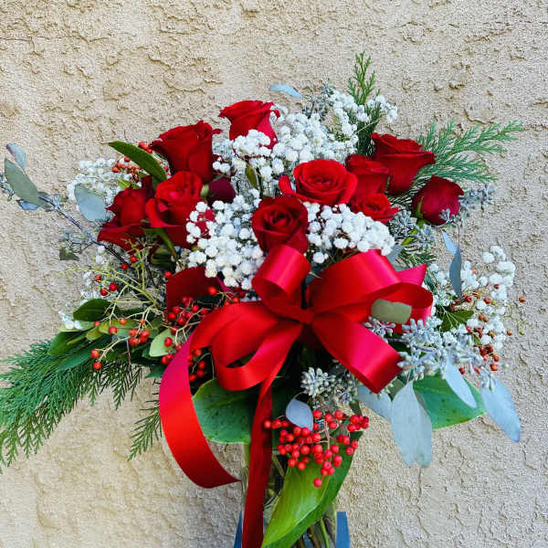 Red roses with baby's breath in a glass vase and red ribbon