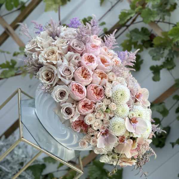 Pastel bouquet of roses, orchids, and white blooms on a mirrored stand