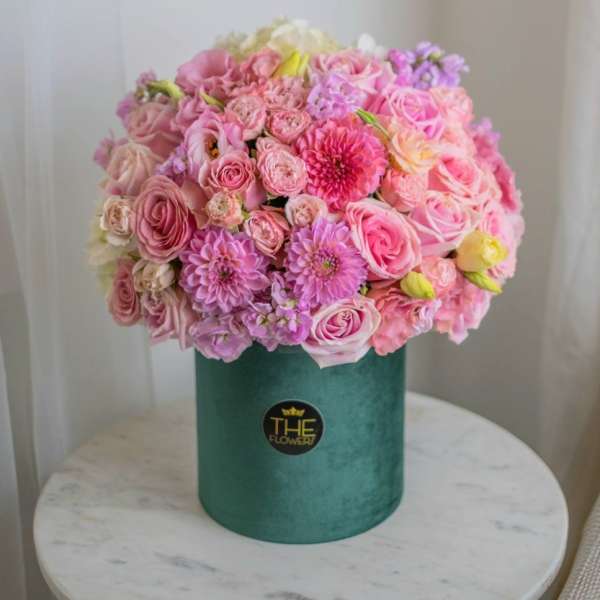 Pink and lavender bouquet in a green hatbox
