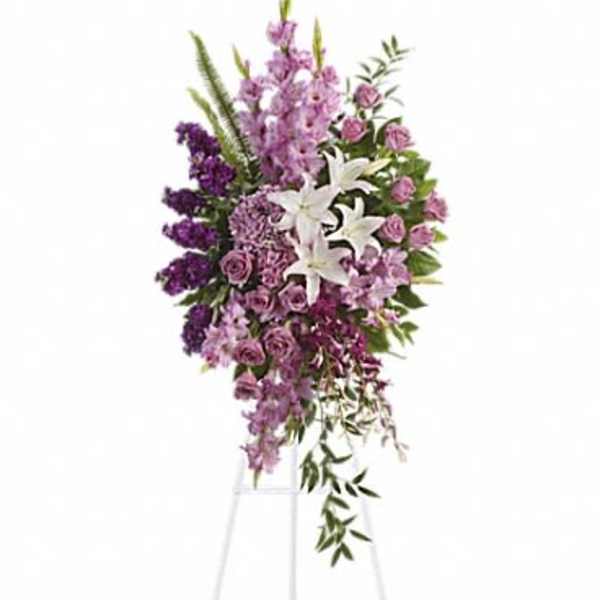 Purple and white funeral spray on a standing easel