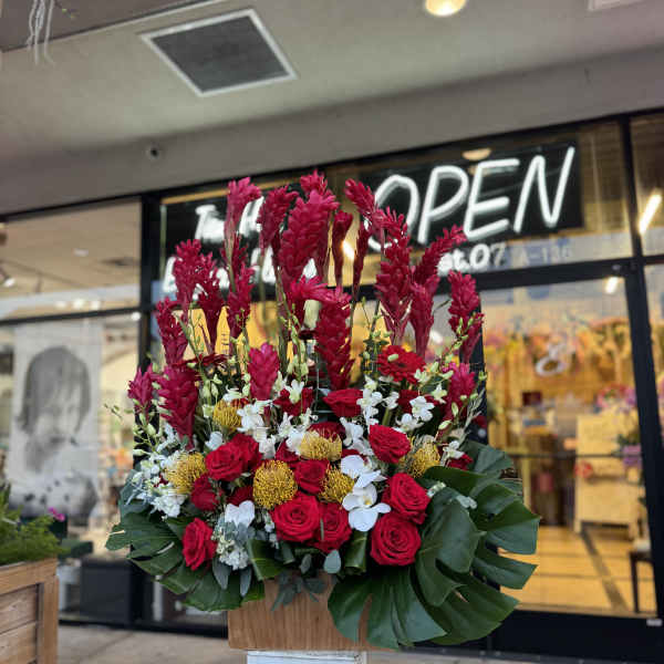 Tall red floral arrangement with roses and white orchids in a wooden container