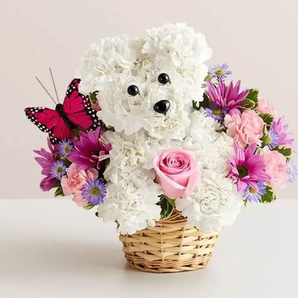 White teddy bear floral arrangement in a wicker basket with pink and purple flowers
