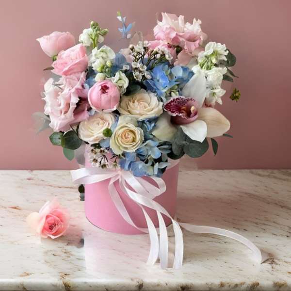 Pink and blue bouquet in a pink hatbox with a white ribbon