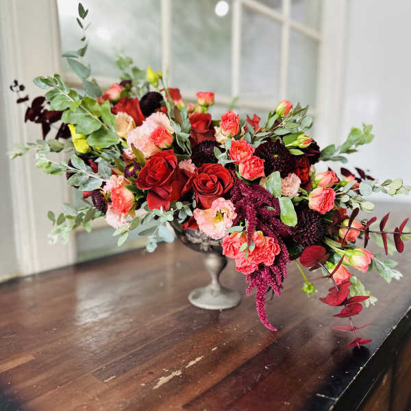 Low floral centerpiece with red and pink blooms in a silver vase