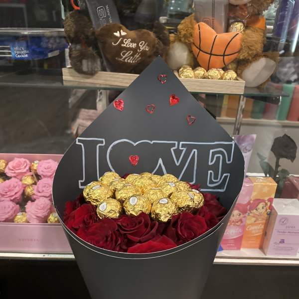 Black cone bouquet with red roses, gold chocolates, and an "I LOVE" topper