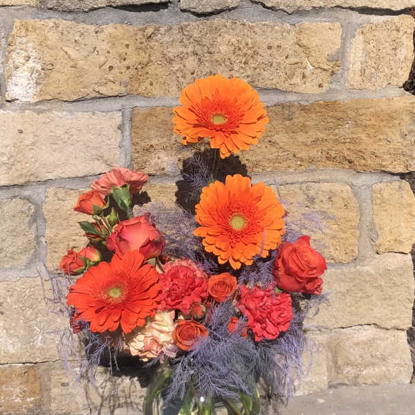 Orange gerberas and red roses in a glass vase