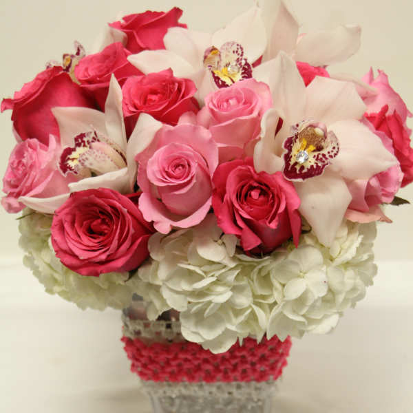 Pink roses and white orchids in a clear square vase