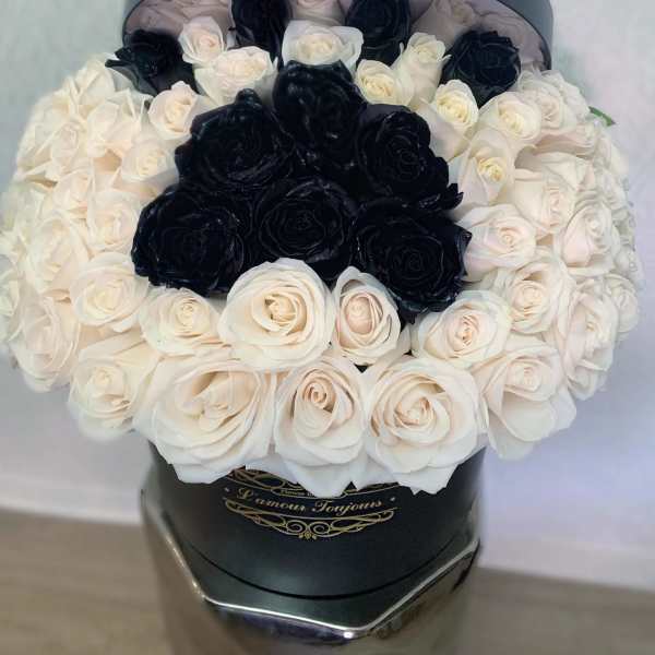 Black and white roses arranged in a round hat box