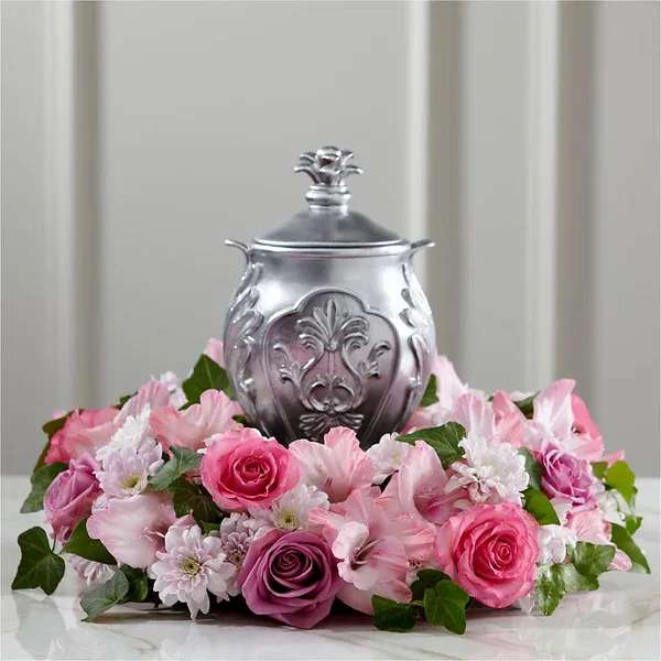 Pink and white floral arrangement around a silver urn