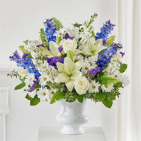 White and blue mixed flower arrangement in a white vase