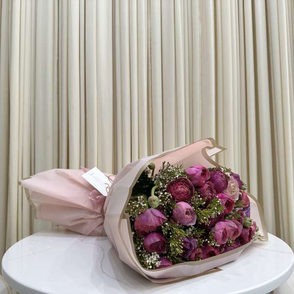 Bouquet of pink and purple flowers wrapped in pale pink paper