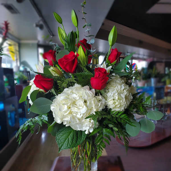 Red roses and white hydrangeas in a clear glass vase