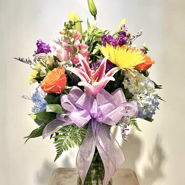 Mixed bouquet in a glass vase with a lavender ribbon